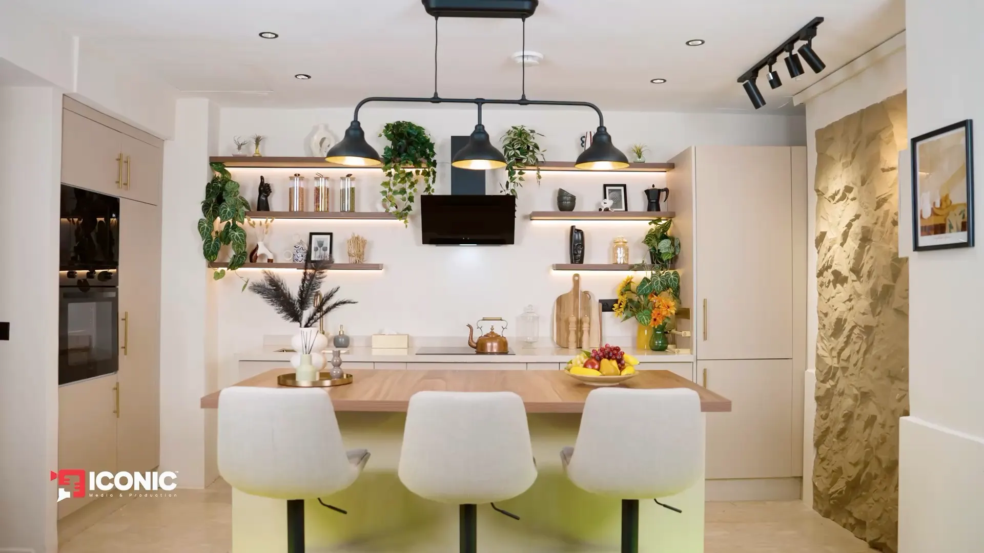 Film du décor ICONIC KITCHEN : îlot, étagères éclairées et cuisine crème et laiton