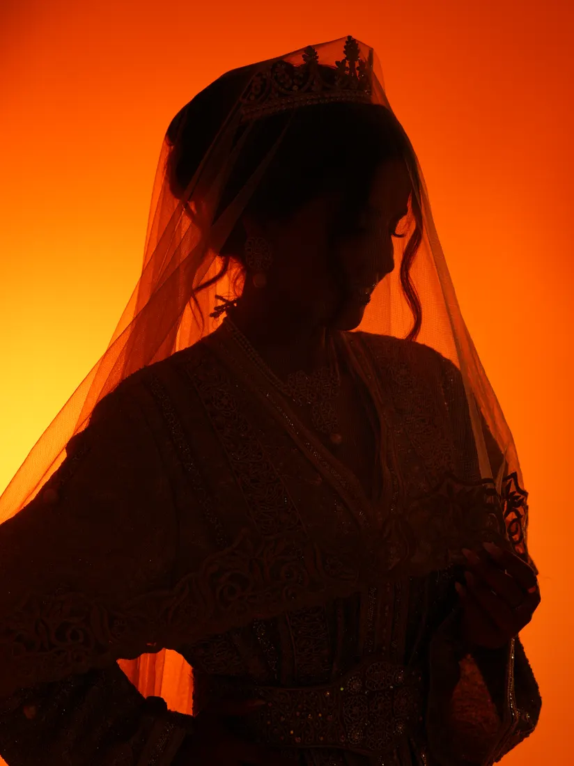 Silhouette voilée en contre-jour sur fond orange.